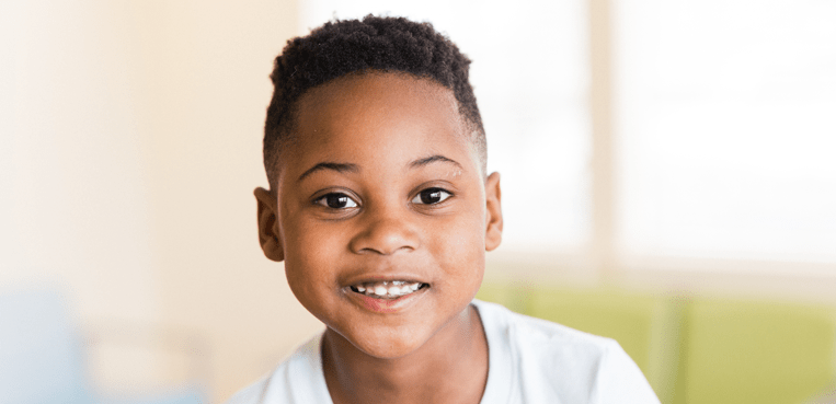 Smiling boy wearing a white shirt.