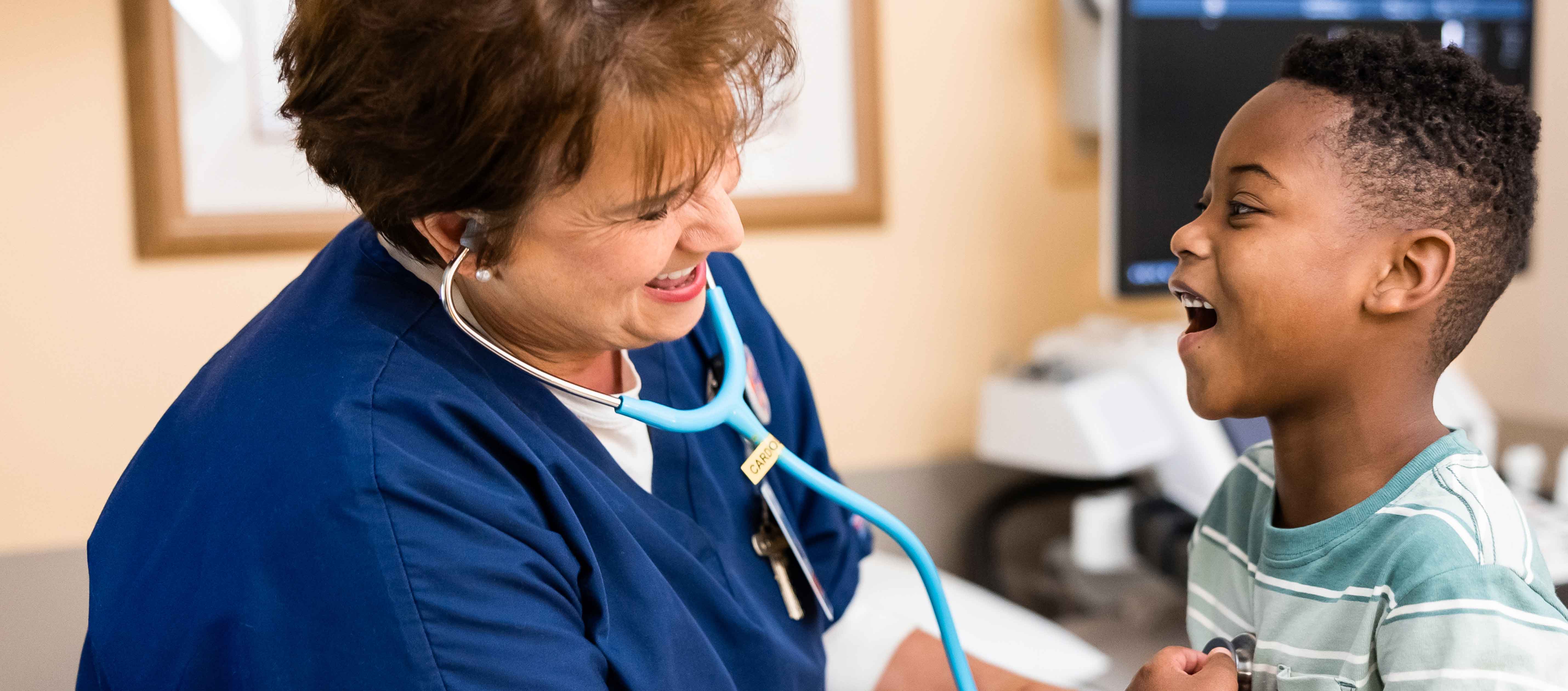 Boy wearing green striped shirt in clinic with nurse.