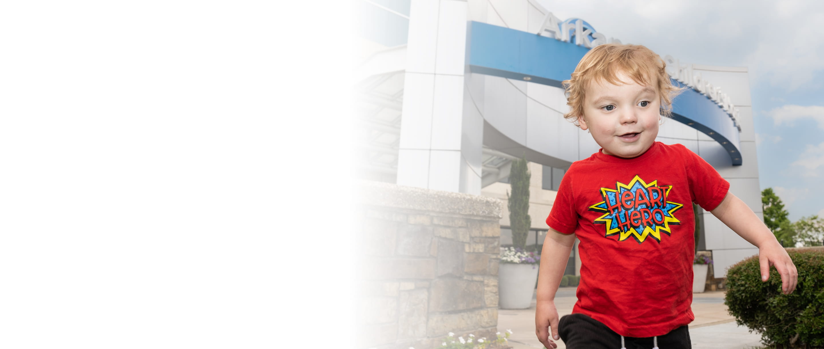 Child wearing a heart hero t-shirt in front of hospital
