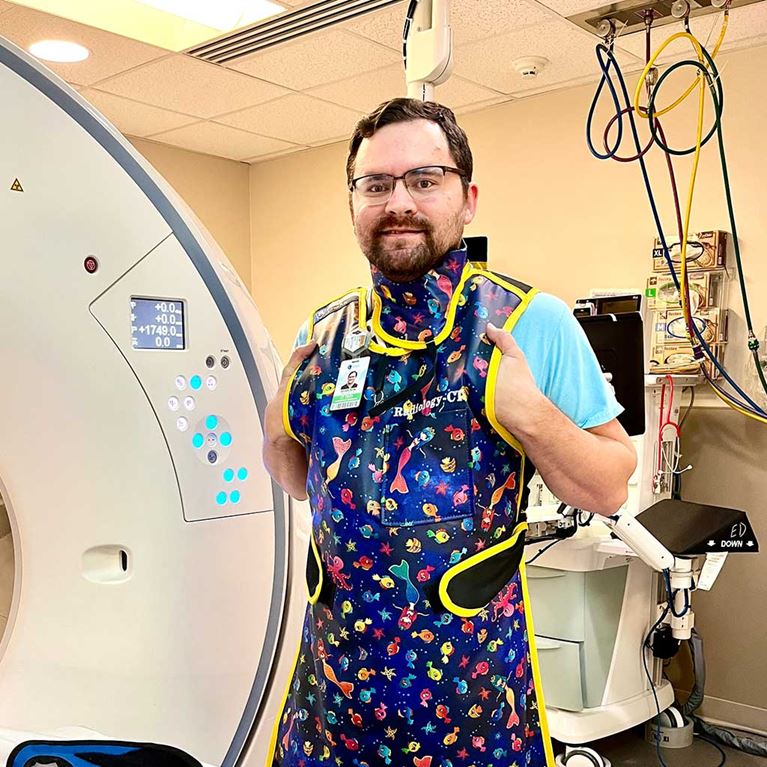 CT technician standing beside CT machine.