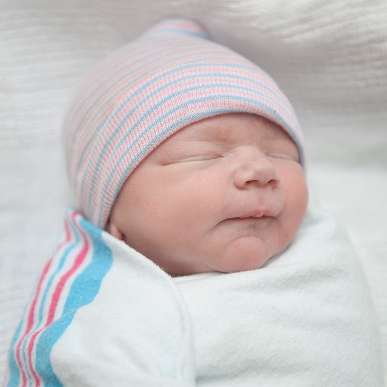 Newborn baby swaddled in hospital blanket.