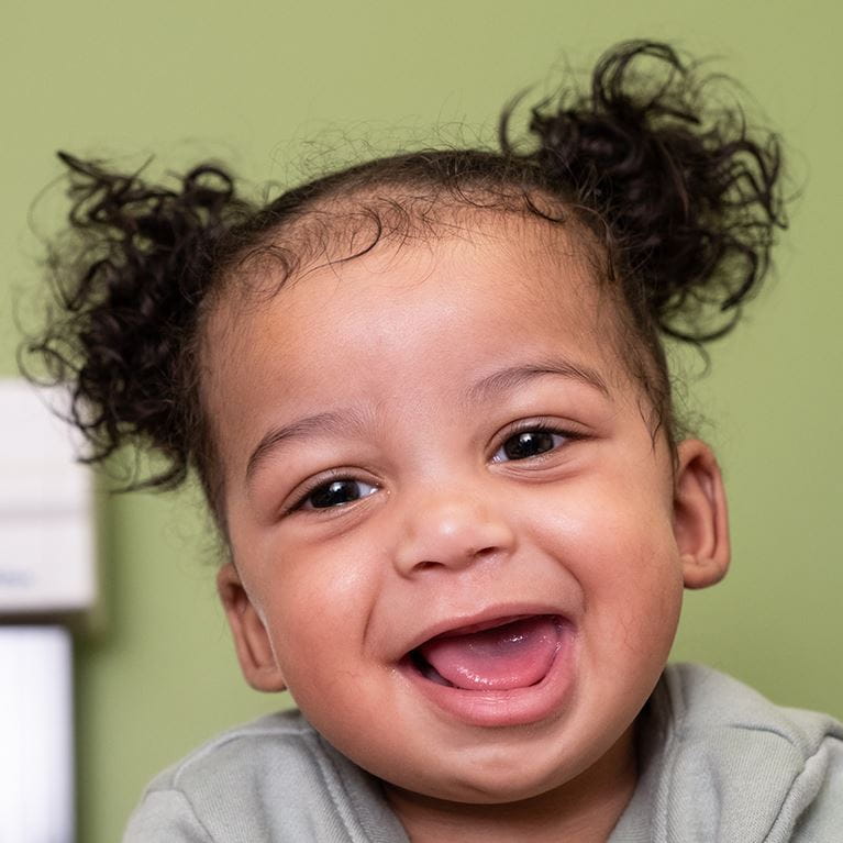 Little boy smiling wearing gray shirt.
