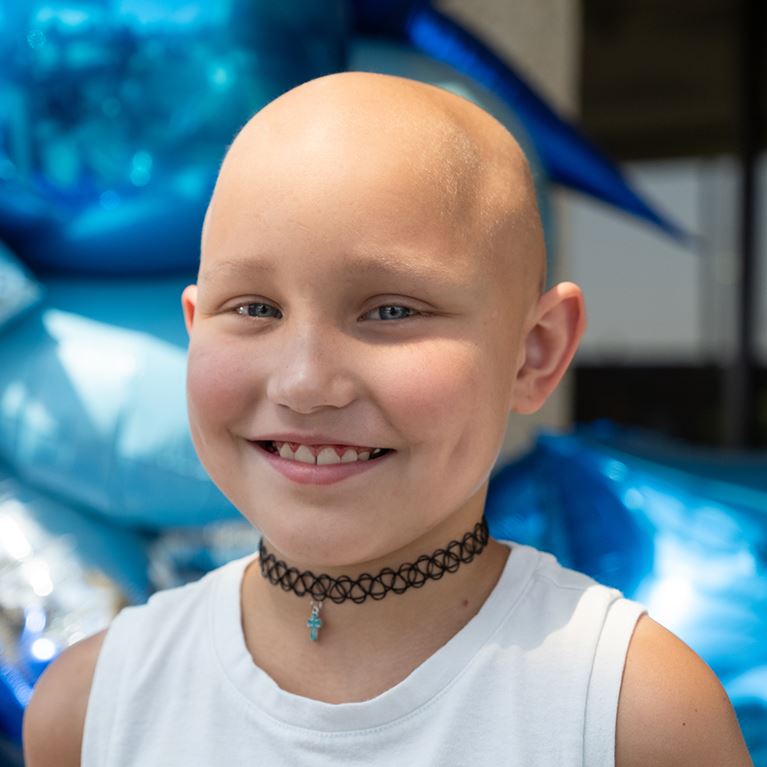  Smiling female cancer patient wearing white shirt.