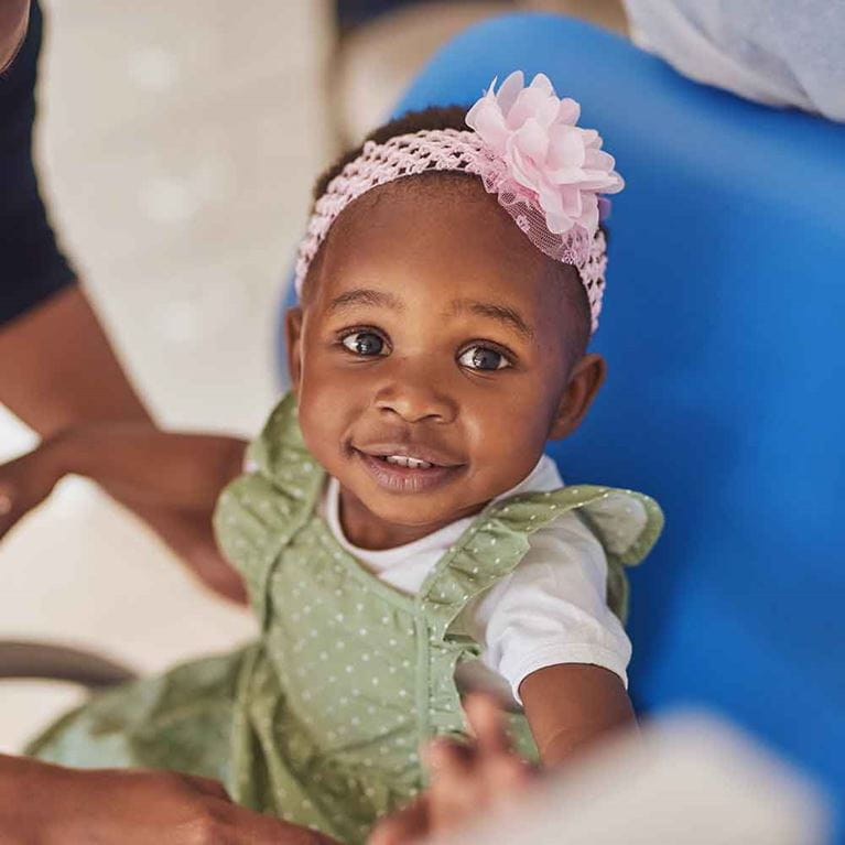 Smilling baby girl wearing a pink bow.