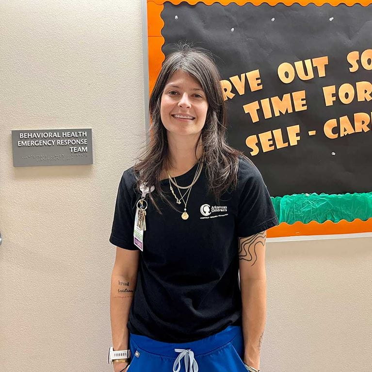 Female team member wearing blue scrub bottoms and black t-shirt.