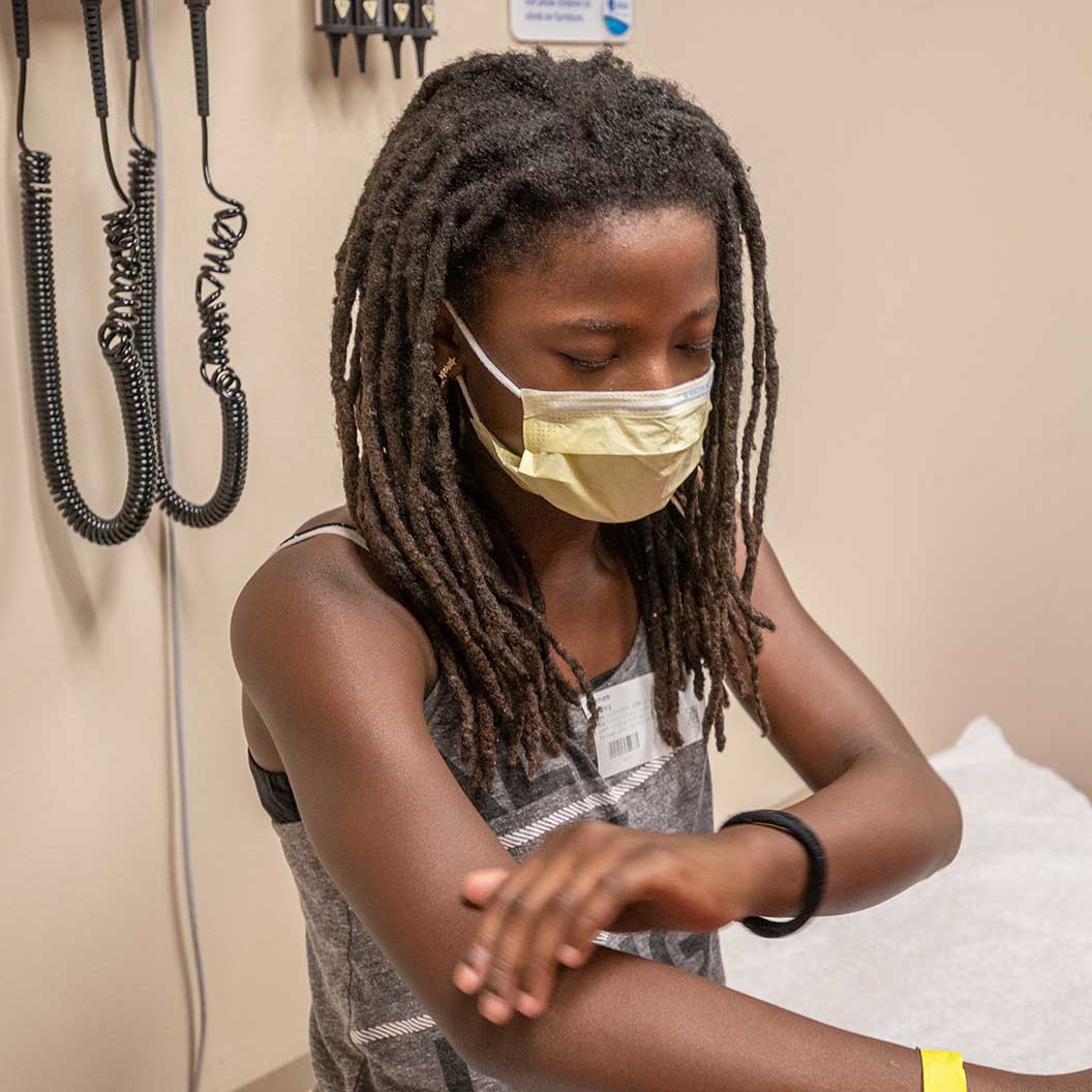 Patient sitting in clinic room getting an exam on arms.