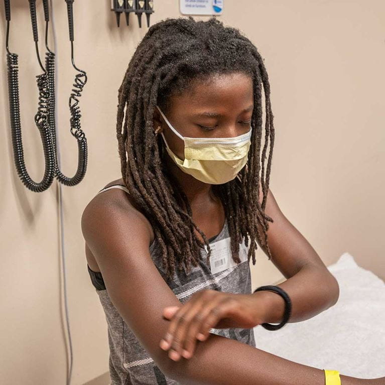 Patient sitting in clinic room getting an exam on arms.