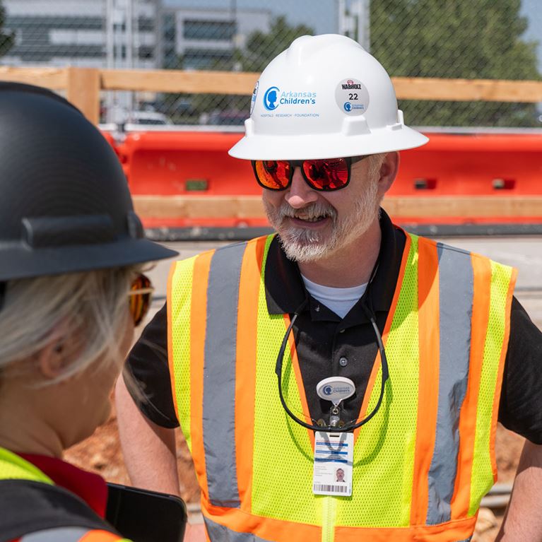 Arkansas Children's employee wearing safety vest and hard hat.