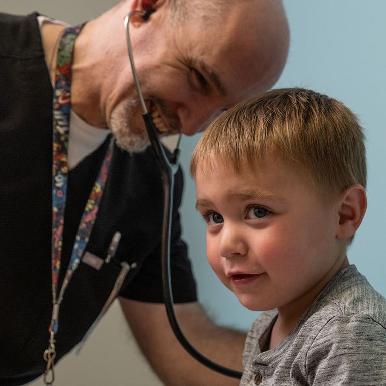 Dr. Oden using stethoscope with young male patient.