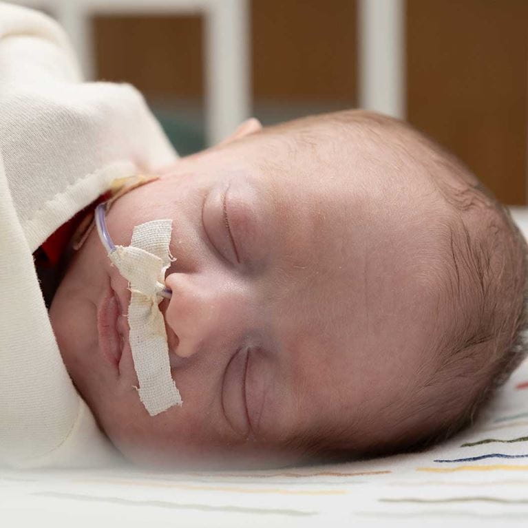 Sleeping infant swaddled in blanket.