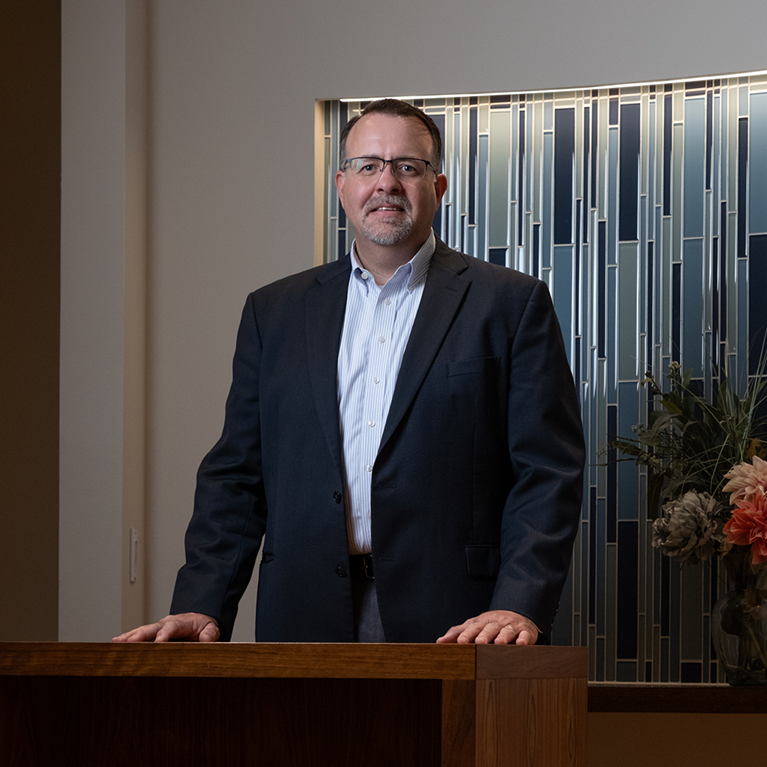 Brent Fairchild standing in the chapel wearing black suit.