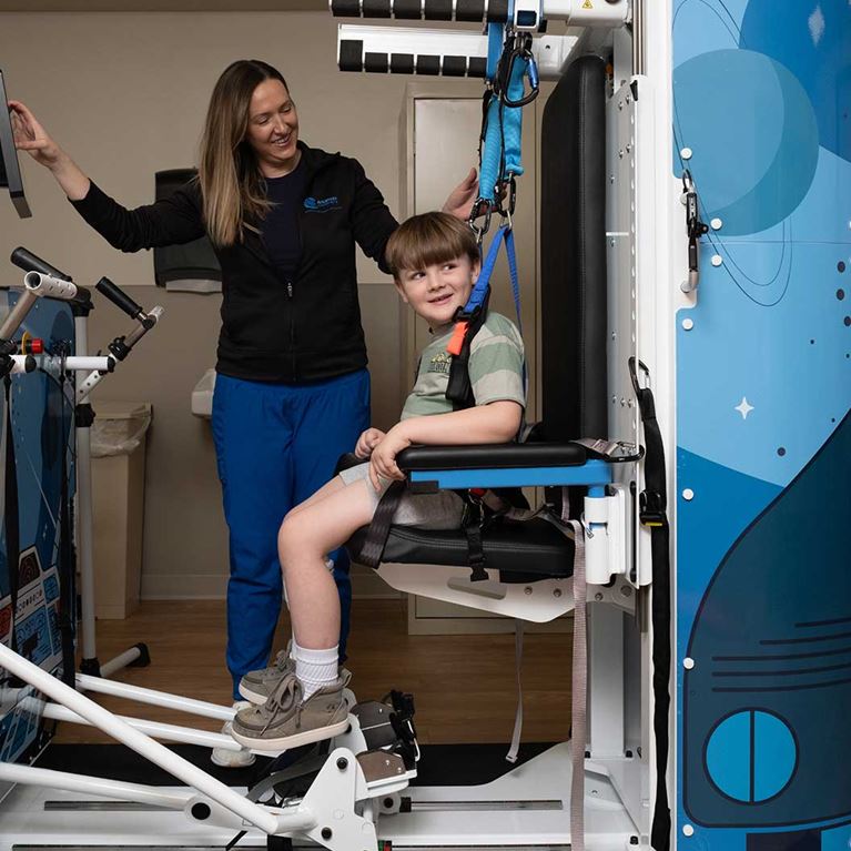 Smiling male patient sitting while using Rise and Walk machine.