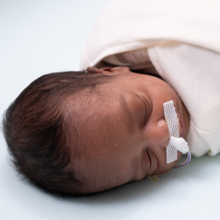 Infant wrapped in white blanket.