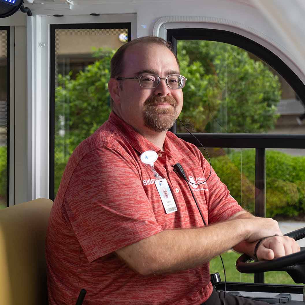 Man sitting in shuttle wearing red shirt.