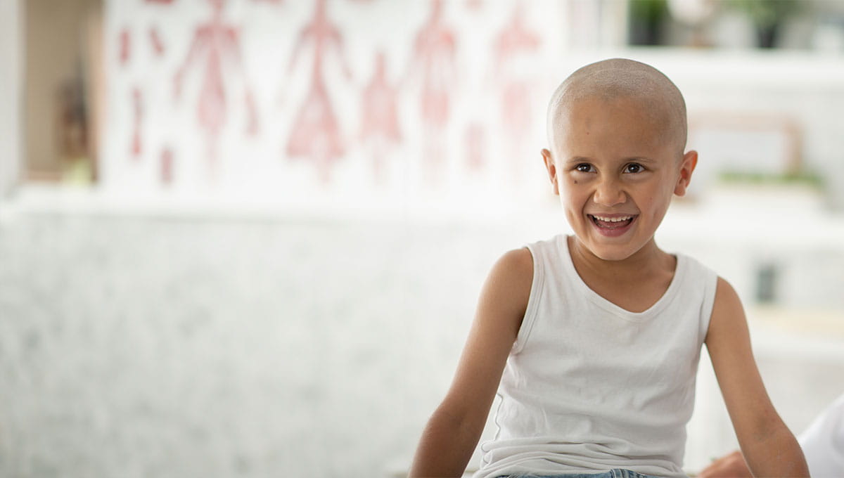 Happy child with no hair wearing white tshirt, smiling and laughing. 