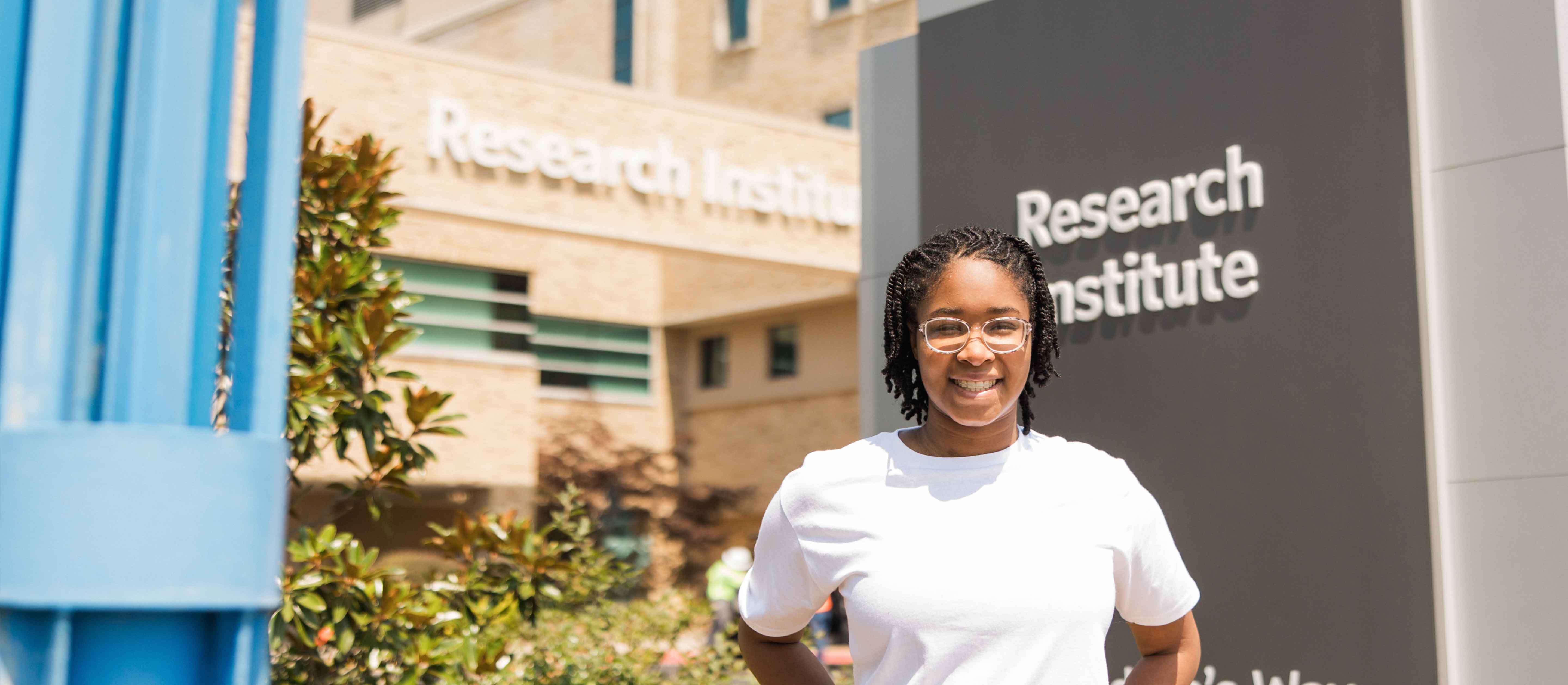 Girl wearing white shirt smiling in front of Research Institute Building