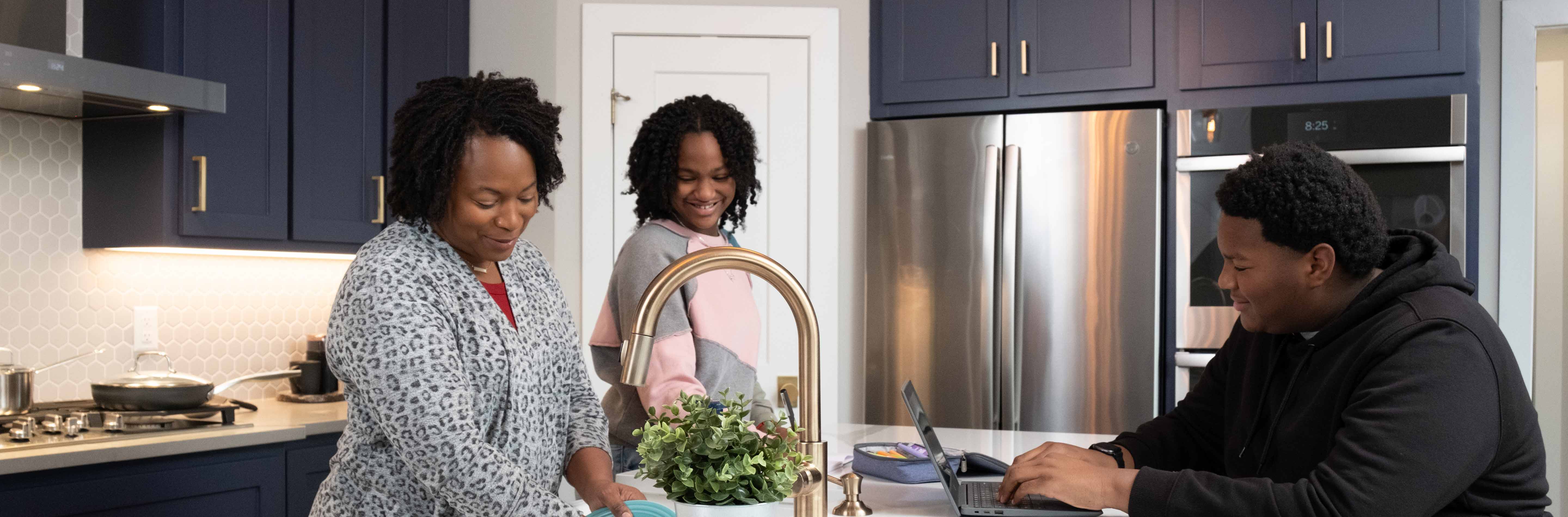 Mom washing dishes in the kitchen while talking to children.