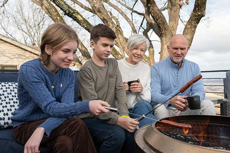 Grandparents sitting outside by the fire with grandchildren.