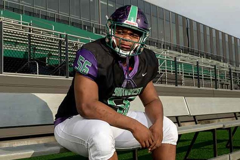 Teenage football player wearing helmet sitting on bench.