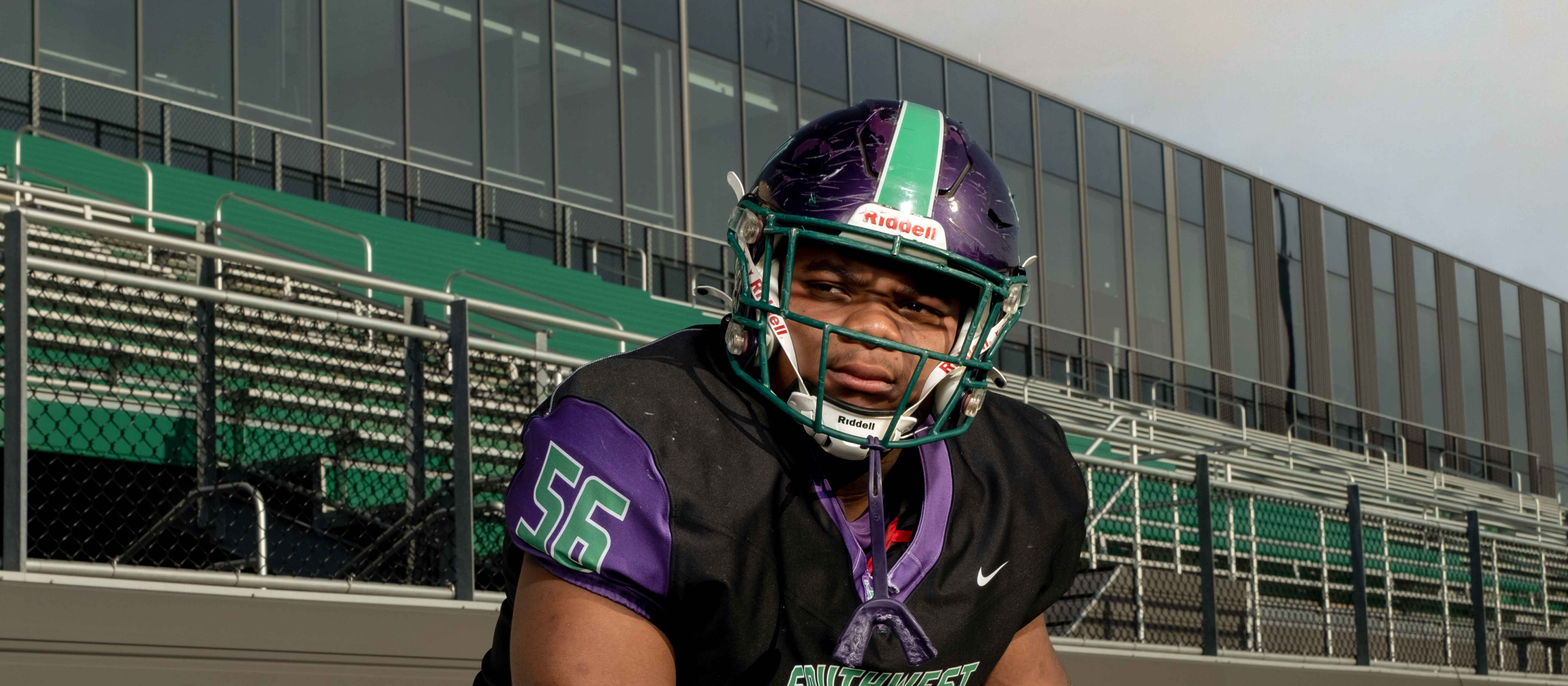 Teenage football player with helmet sitting on bench.