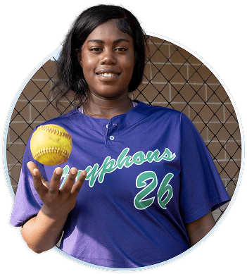 Softball player in purple jersey throwing softball in the air.