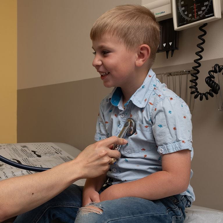 Smiling boy wearing blue shirt in clinic.
