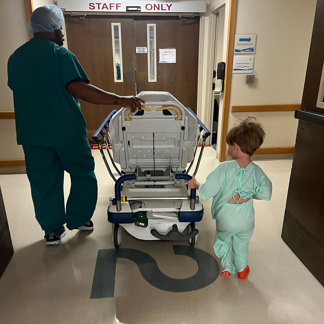 Toddler male patient helping push bed back to the operating room.