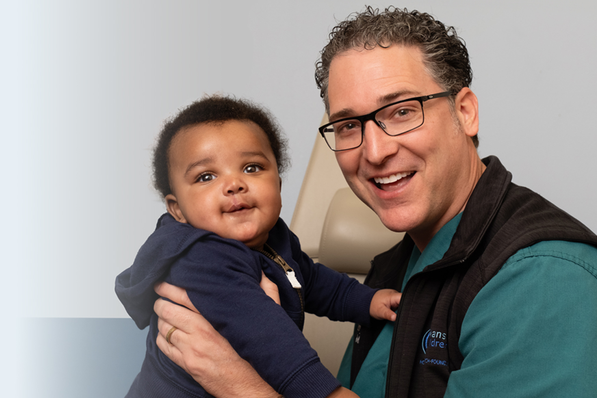 Doctor holding African American boy in clinic.