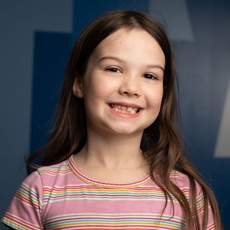 Smiling toddler girl wearing pink striped top.