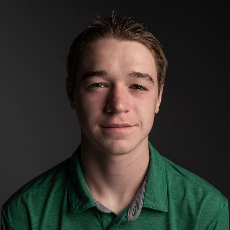 Teenage boy with brown hair wearing green shirt.
