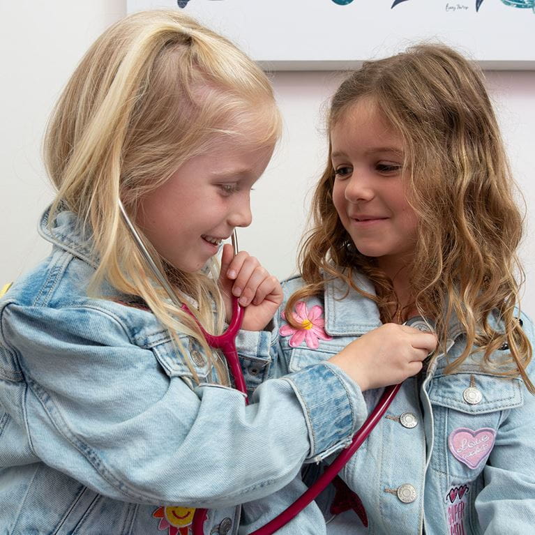 Two young sisters using stethoscopes.