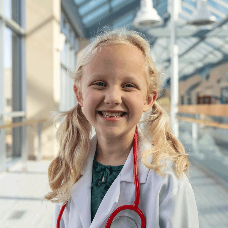 Young blonde girl with pigtails and a doctor coat.