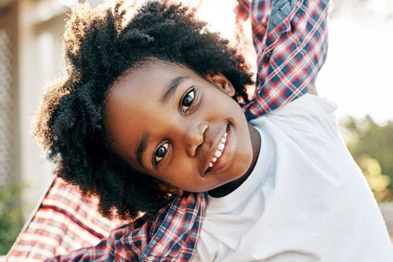 Boy in white shirt smiling at camera.
