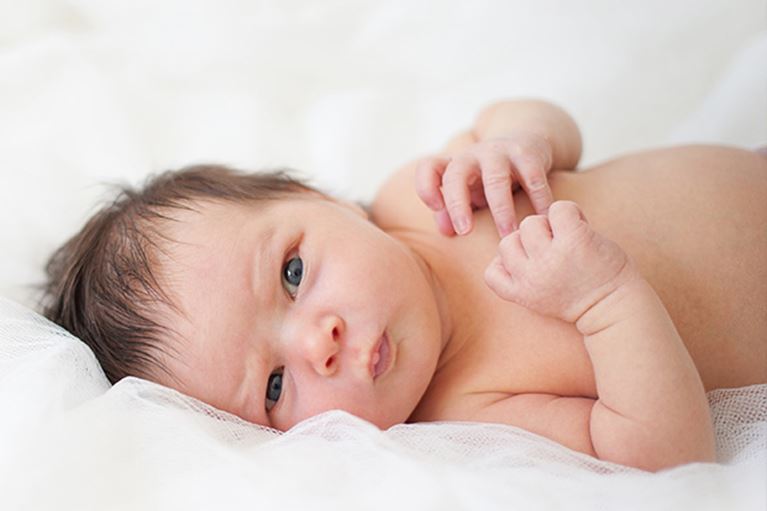 Infant child on white blanket.