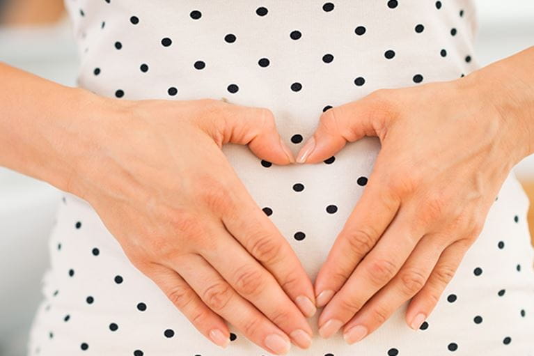 Pregnant mom with hands forming heart over belly.