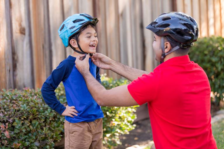 Dad putting a helmet on his son