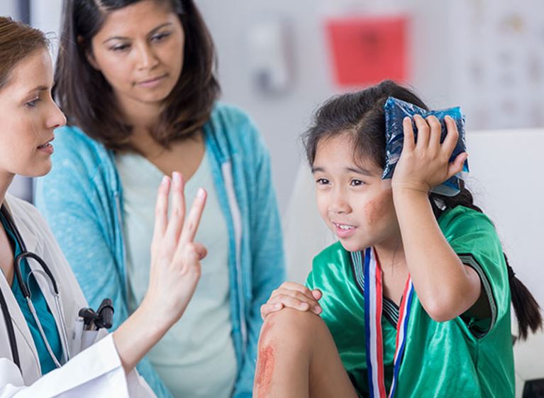 Photo of a young athlete holding an ice pack to her head