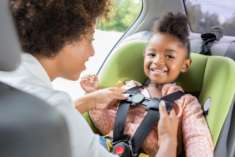 Mom buckling a child into a carseat
