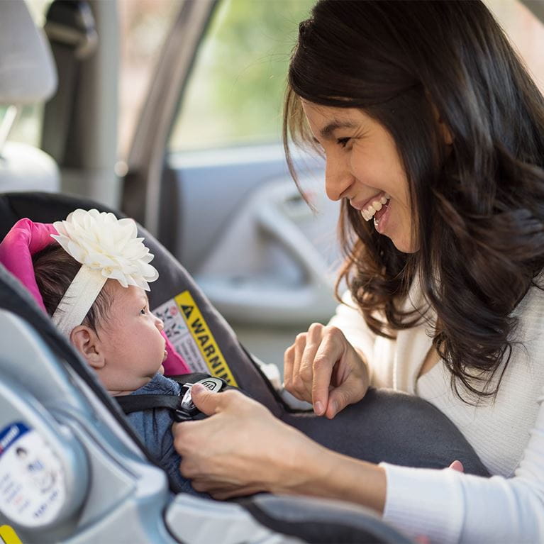 Woman putting child in carseat.