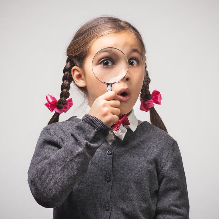 Girl with braided pigtails holding magnifying glass