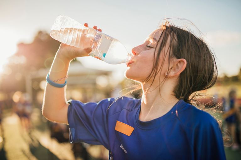 Female outside drinking from a water bottle