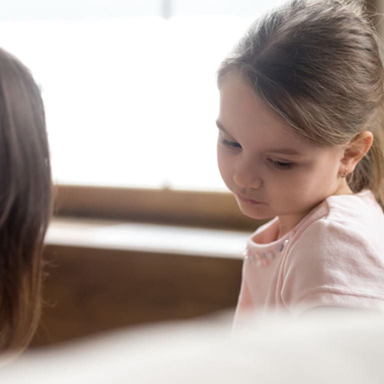Small girl being comforted by her mother.