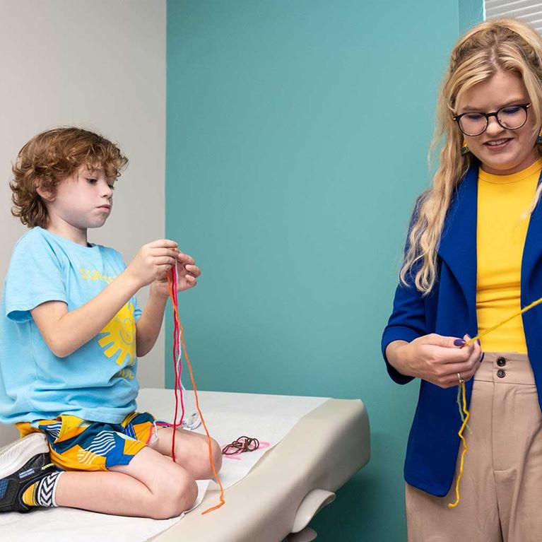 Male GI patient playing with yarn during office visit.