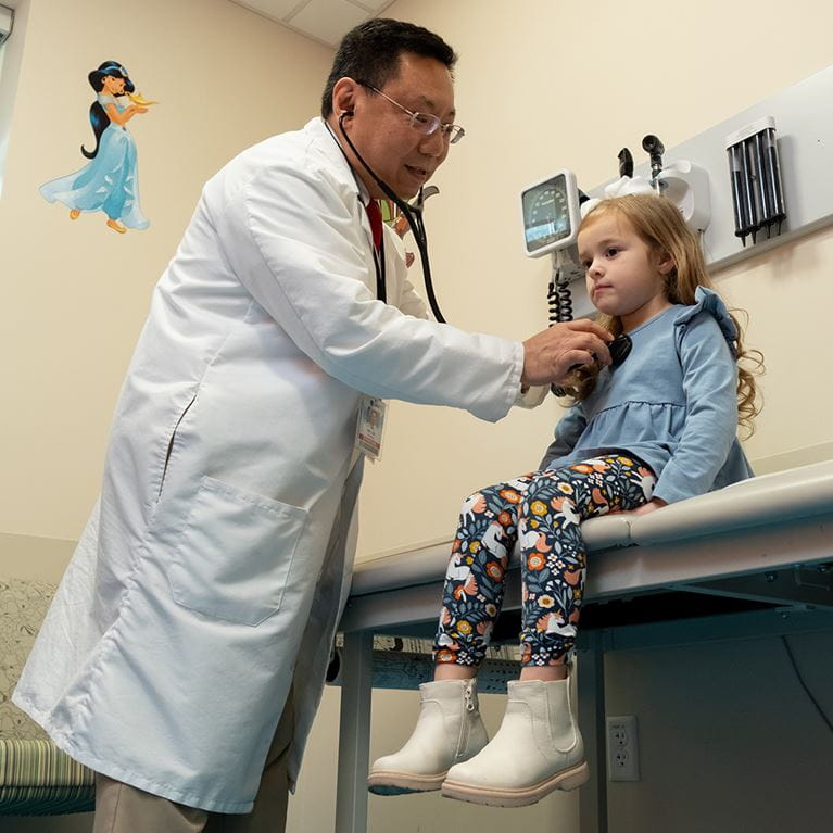 Dr. Sam Lee listening to young female patients heart with stethoscope.