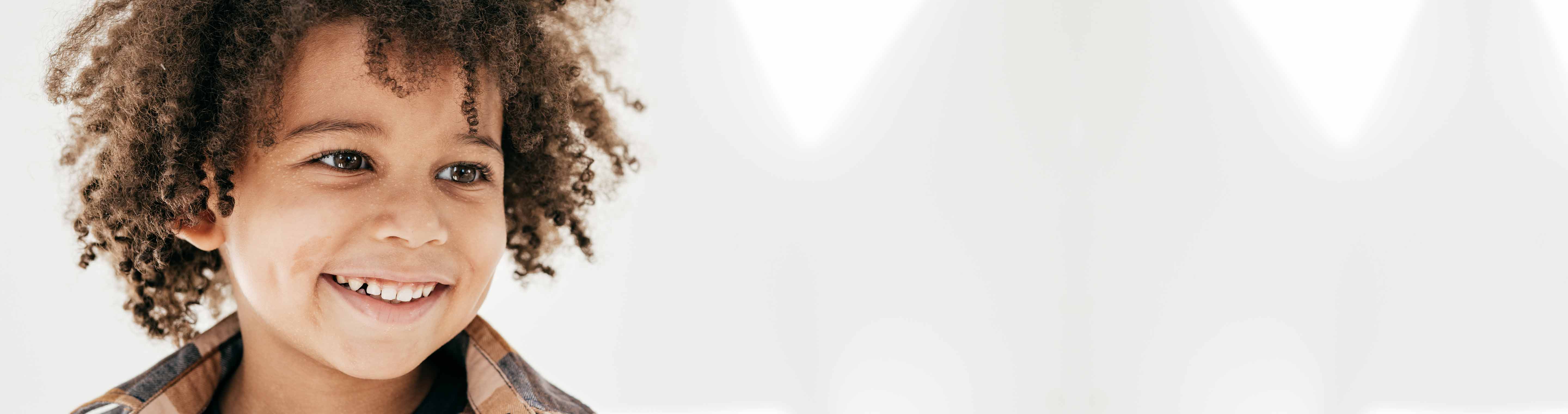 Young child with curly hair smiling with dimples.