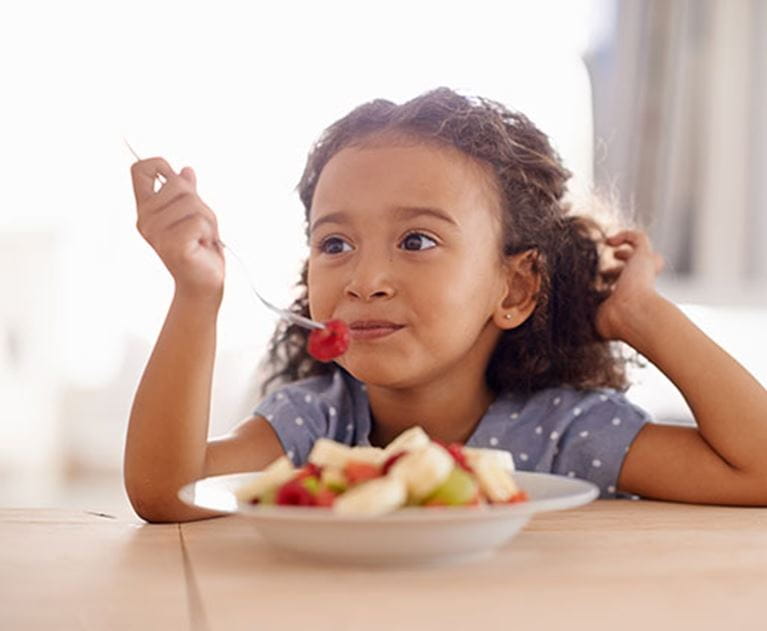Girl eating a bowl of fruit.