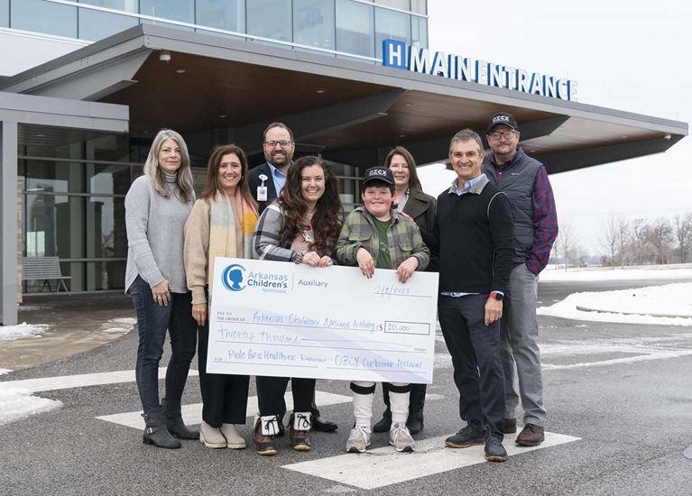 Group of people holding large check.