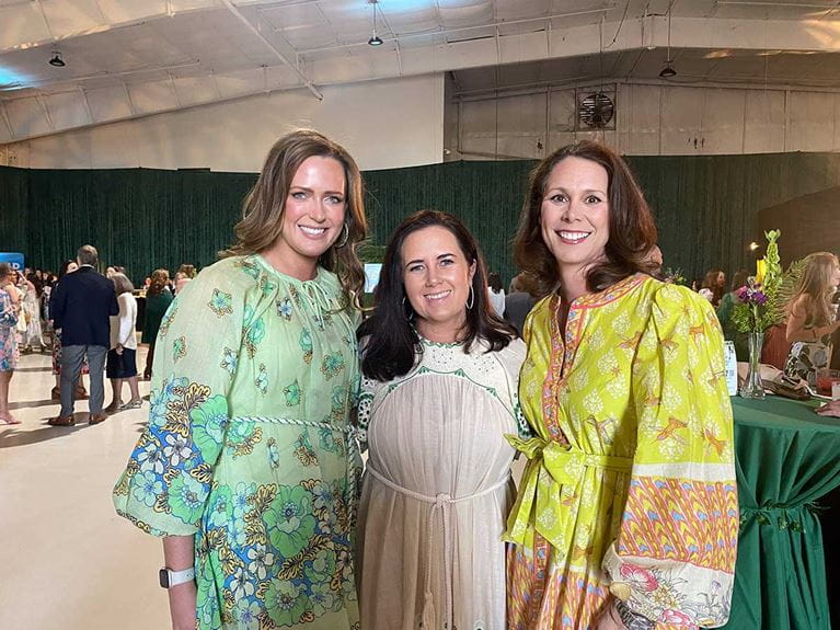 A group of three ladies in colorful dresses posing for a photo. 