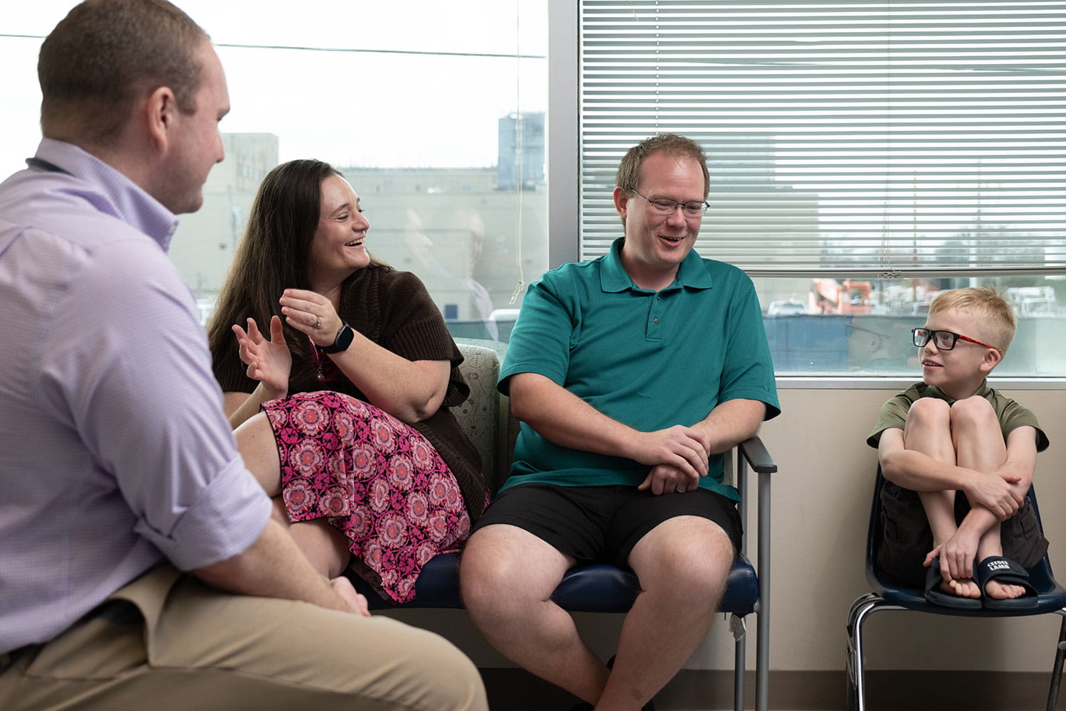 Happy mom and dad along with young son visiting with pediatric doctor.