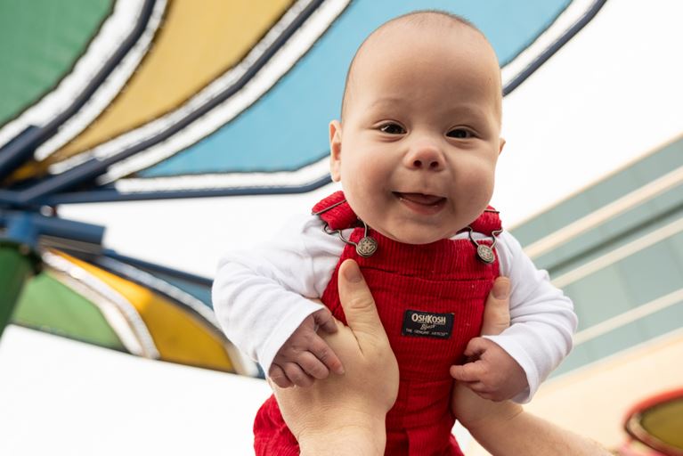 Happy baby wearing red overalls. 